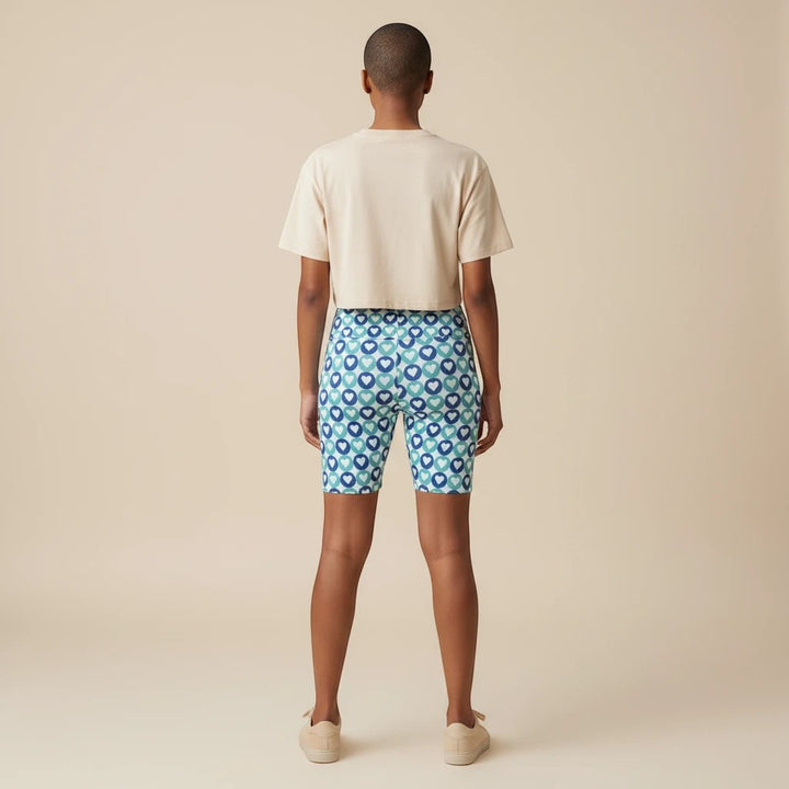 Sea Dragon Dreams women's workout shorts featuring a blue heart pattern, worn with a beige crop top, back view.