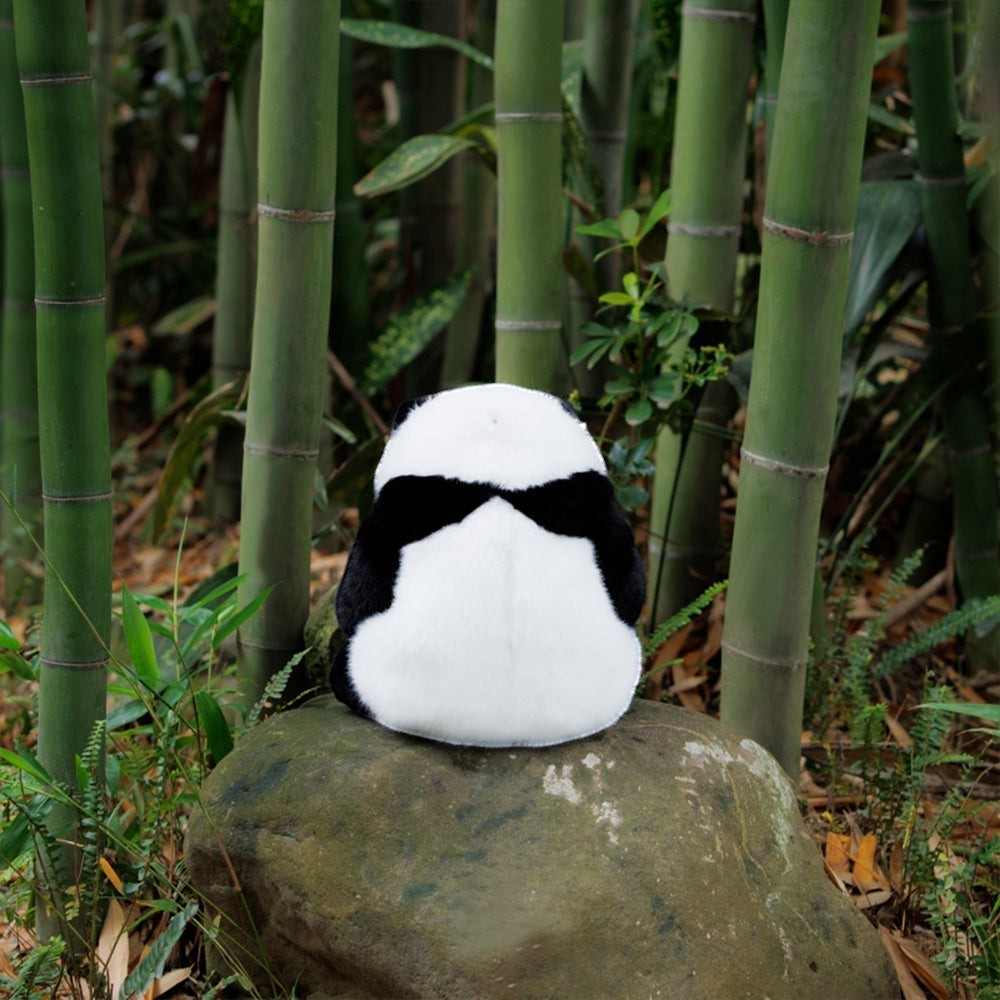 Sea Dragon Dreams Hehua panda plush backpack sitting on a mossy rock in a bamboo forest, showing its soft back view.