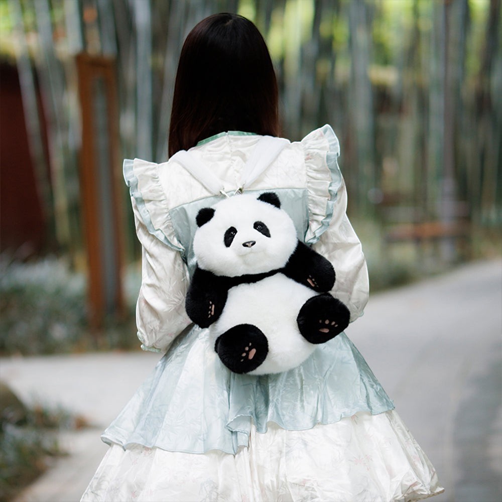 Sea Dragon Dreams Hehua panda plush mini backpack worn by a person in a light blue dress in a bamboo forest setting.