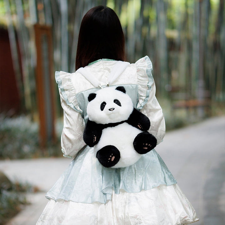 Sea Dragon Dreams Hehua panda plush mini backpack worn by a person in a light blue dress in a bamboo forest setting.
