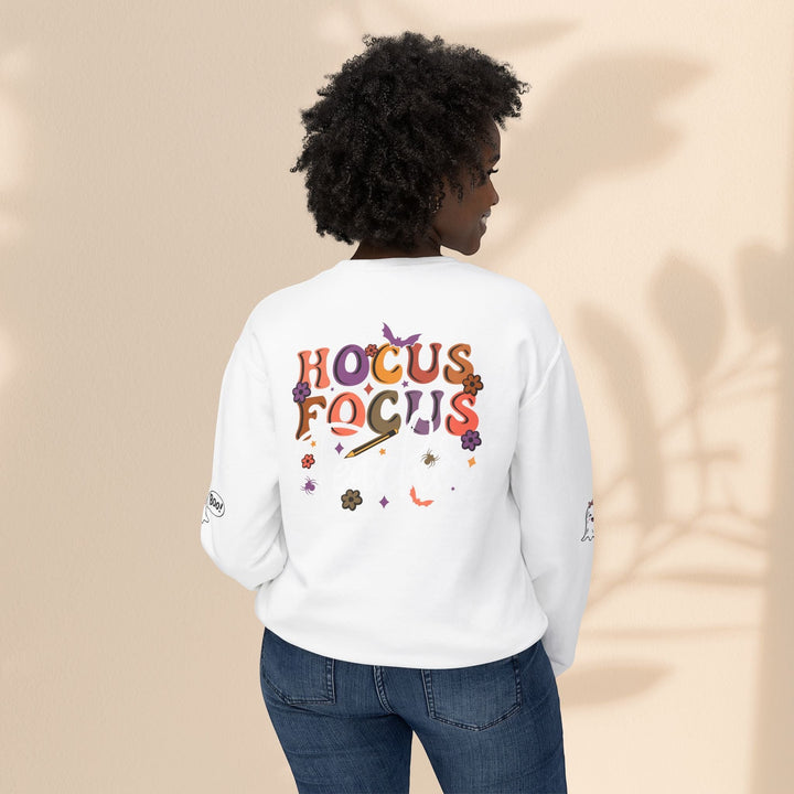 Sea Dragon Dreams white crewneck sweatshirt with Hocus Focus teacher graphic on back, worn by a woman with curly hair.