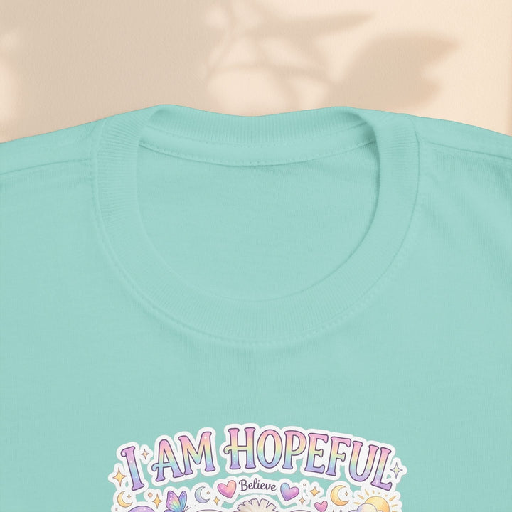 Sea Dragon Dreams toddler tee in light teal cotton with I Am Hopeful graphic featuring Hope Bunny and pastel icons.