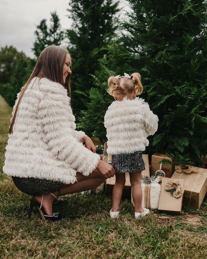 Sea Dragon Dreams ivory faux shag layered jackets worn by a mother and daughter in a festive outdoor setting.
