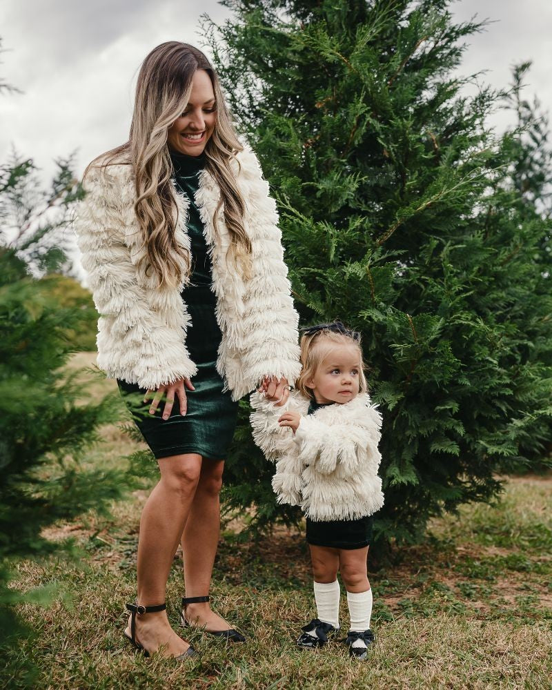 Sea Dragon Dreams ivory faux shag layered jackets worn by a mother and daughter in a festive outdoor setting.