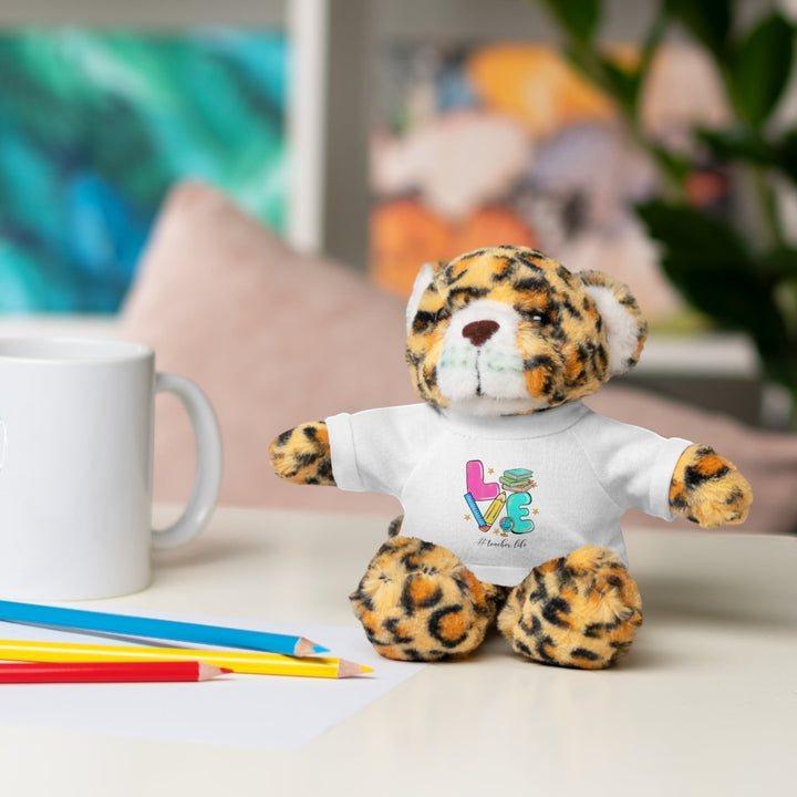 Sea Dragon Dreams plush jaguar stuffed animal wearing a white t-shirt with Love Teacher Life graphic on a desk
