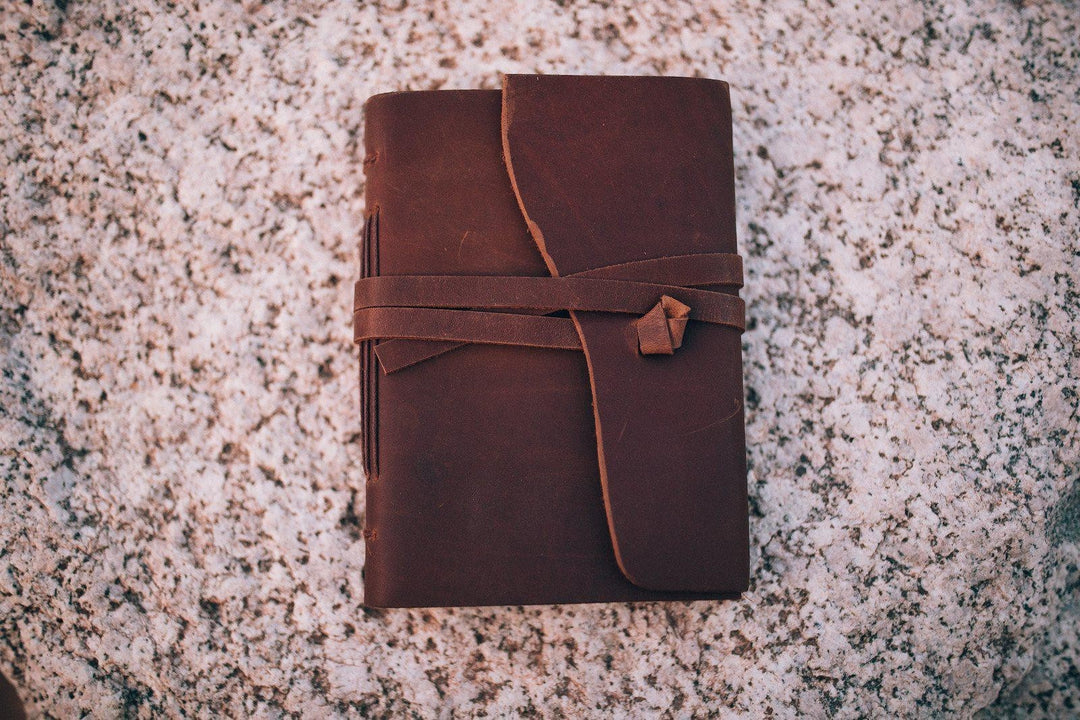 Sea Dragon Dreams Kodiak leather travel journal with a rustic wrap-around tie closure on a textured stone surface