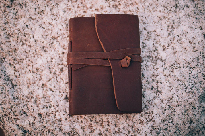 Sea Dragon Dreams Kodiak leather travel journal with a rustic wrap-around tie closure on a textured stone surface