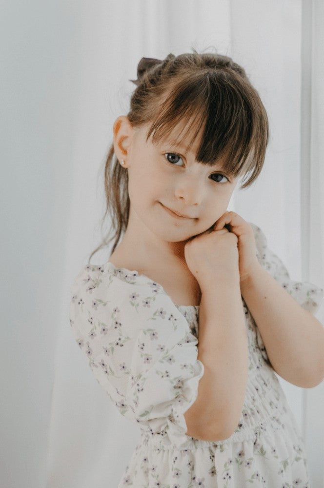A young girl wearing a Sea Dragon Dreams lavender floral Katherine dress with a soft, feminine, flowy silhouette.