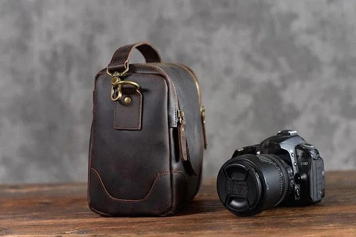 Sea Dragon Dreams Calista handcrafted dark brown full-grain leather camera bag with brass hardware next to a DSLR