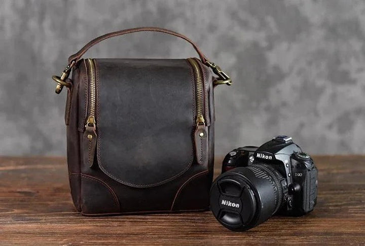 Sea Dragon Dreams Calista handcrafted dark brown full-grain leather camera bag with brass zippers next to a DSLR