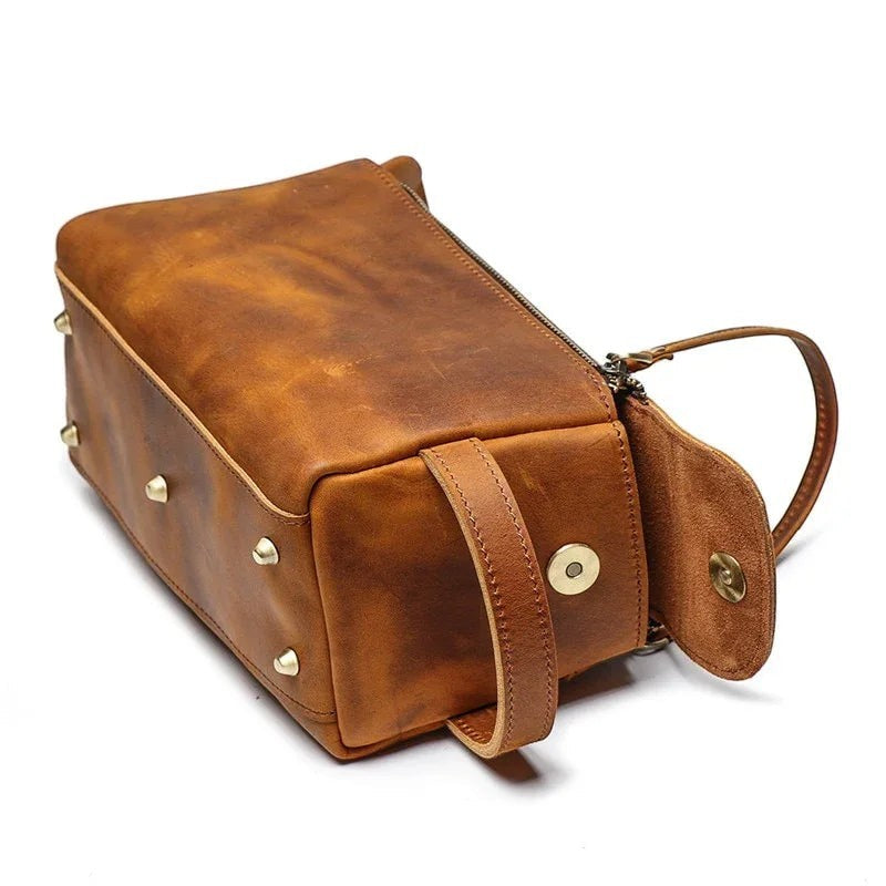 Sea Dragon Dreams handmade brown leather dopp kit with brass studs and side handle on a white background