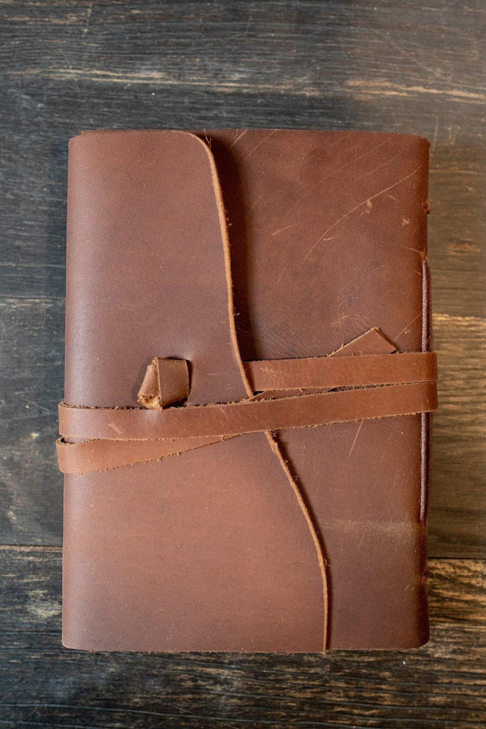 Sea Dragon Dreams Kodiak leather travel journal with a rustic brown wrap-around tie closure on a dark wooden surface.