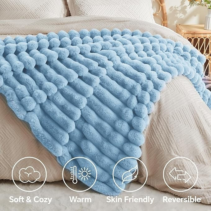 Sea Dragon Dreams light blue faux rabbit fur throw blanket with 3D striped texture draped over a bed.