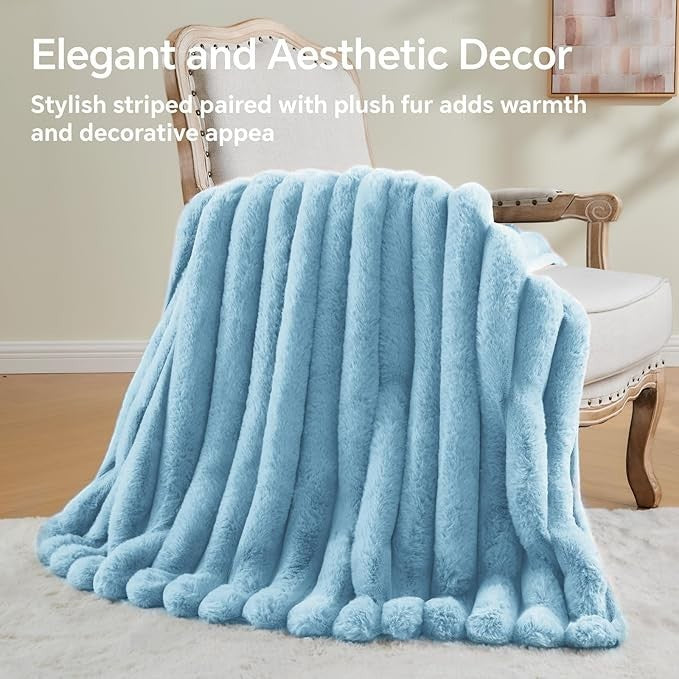 Sea Dragon Dreams light blue faux rabbit fur throw blanket with 3D striped texture draped over a vintage chair.