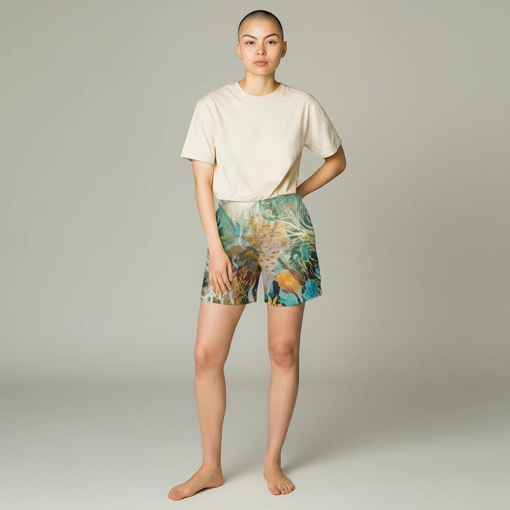 Model wearing Sea Dragon Dreams marine life print swim shorts with a beige t-shirt in a studio setting.