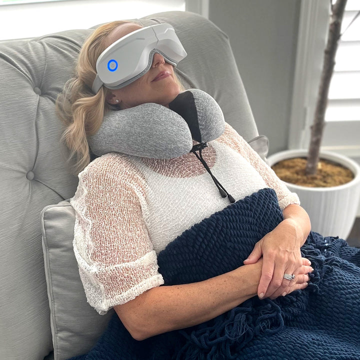 Sea Dragon Dreams grey memory foam travel pillow providing neck support to a woman wearing a white eye massager.