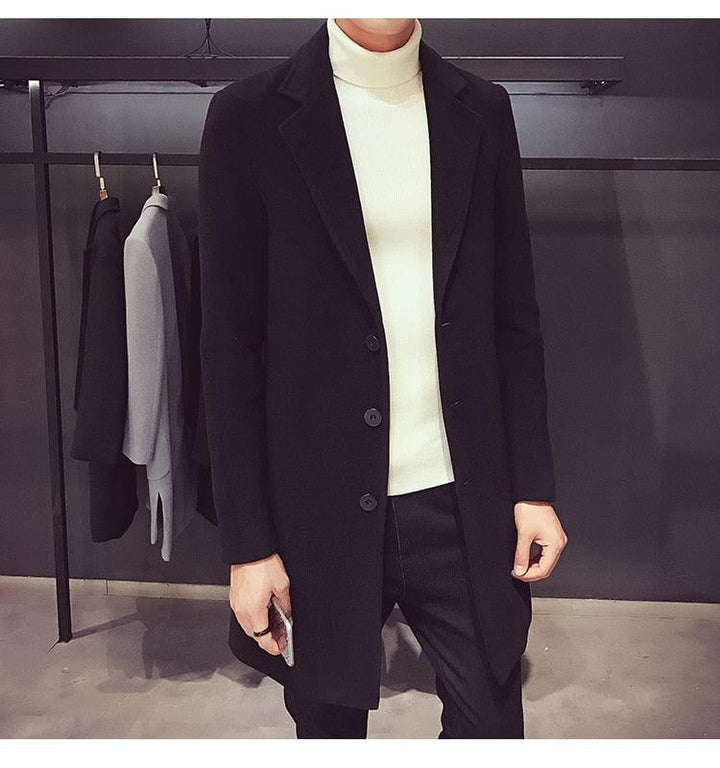 Sea Dragon Dreams men's black cotton trench coat with a turn-down collar worn over a white turtleneck sweater.