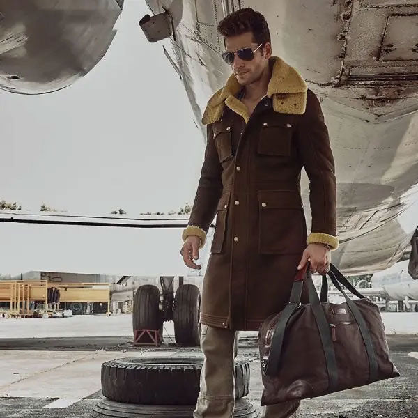Sea Dragon Dreams men's brown shearling parka with sheepskin wool lining and hood, worn by a man near an airplane.