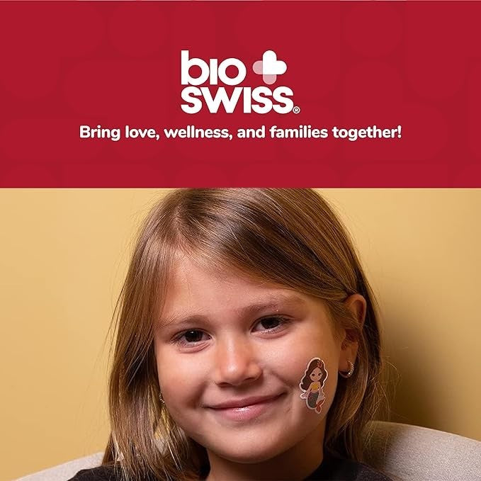 A young girl with a Sea Dragon Dreams BioSwiss mermaid bandage on her cheek, smiling in a bright, friendly setting.