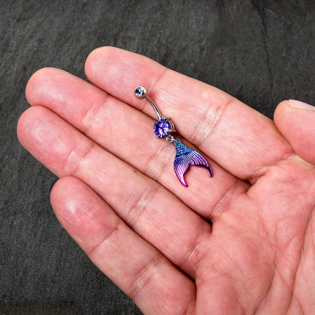 Sea Dragon Dreams purple mermaid tail belly ring with aqua and pink enamel details and a sparkling purple gemstone.