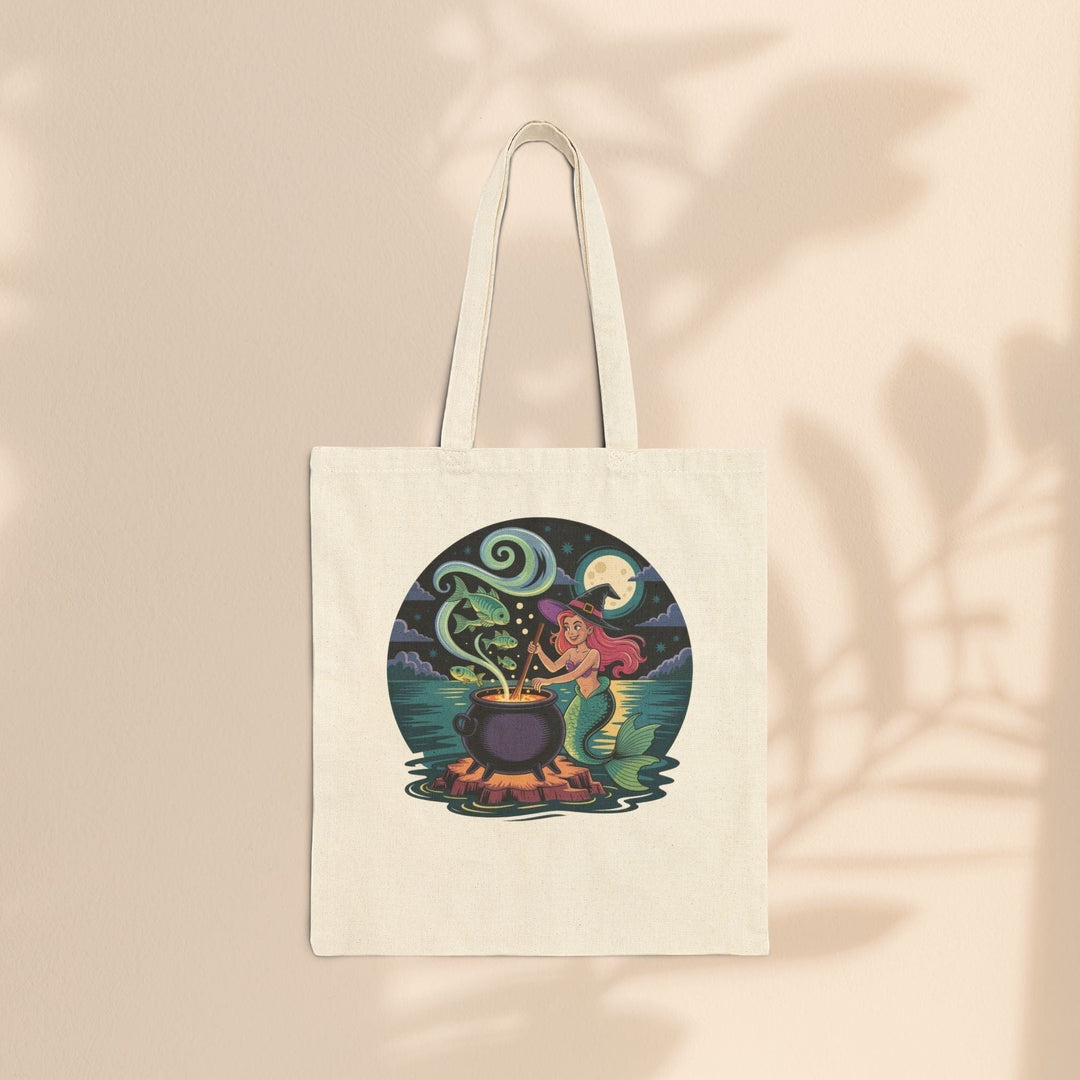 Sea Dragon Dreams natural cotton canvas tote bag featuring a whimsical mermaid witch stirring a magical cauldron