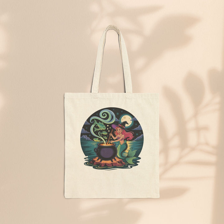 Sea Dragon Dreams natural cotton canvas tote bag featuring a whimsical mermaid witch stirring a magical cauldron