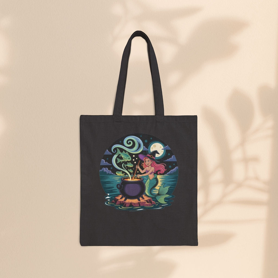 Sea Dragon Dreams black cotton canvas tote bag featuring a whimsical mermaid witch stirring a magical cauldron