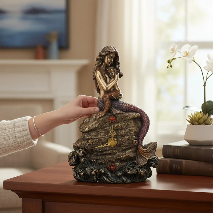 Sea Dragon Dreams mermaid mother and baby clock featuring a sculpted bronze-toned figure on a rocky ocean base.