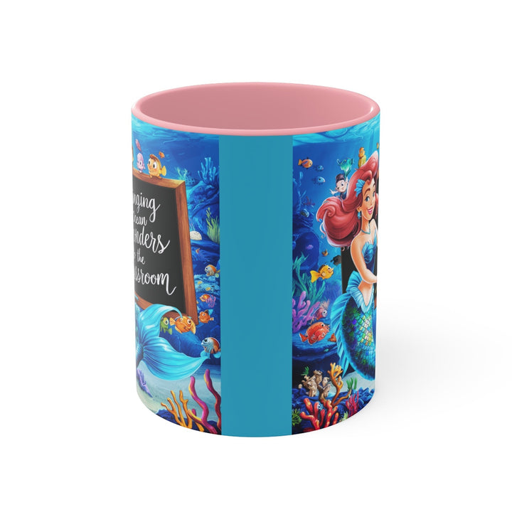 Sea Dragon Dreams ceramic mug with pink interior featuring a mermaid and ocean classroom scene illustration