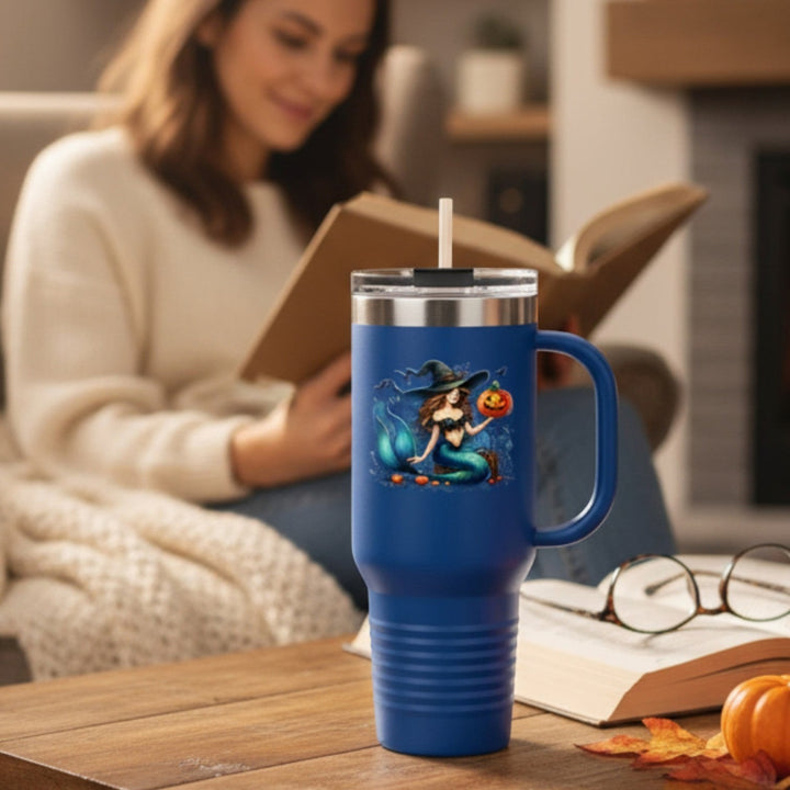 Sea Dragon Dreams 40oz blue insulated travel mug with a mermaid and pumpkin Halloween design on a cozy living room table