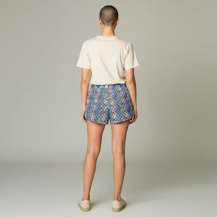Sea Dragon Dreams women's casual shorts featuring an iridescent rainbow mermaid scale print, back view on a model.