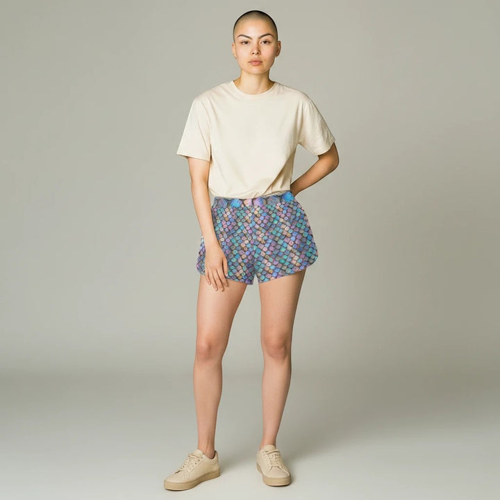 Model wearing Sea Dragon Dreams iridescent mermaid scale print casual polyester shorts with a beige t-shirt.