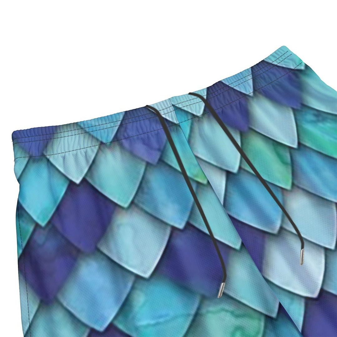 Sea Dragon Dreams men's swim shorts featuring a vibrant blue and teal mermaid scale pattern with a black drawstring