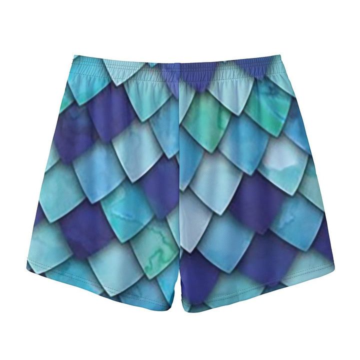 Sea Dragon Dreams men's swim shorts featuring a vibrant blue and teal mermaid scale pattern on polyester fabric.