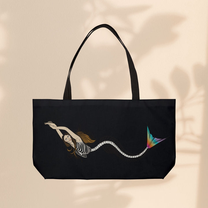 Sea Dragon Dreams weekender tote bag featuring a mermaid skeleton illustration with a vibrant rainbow tail on black.