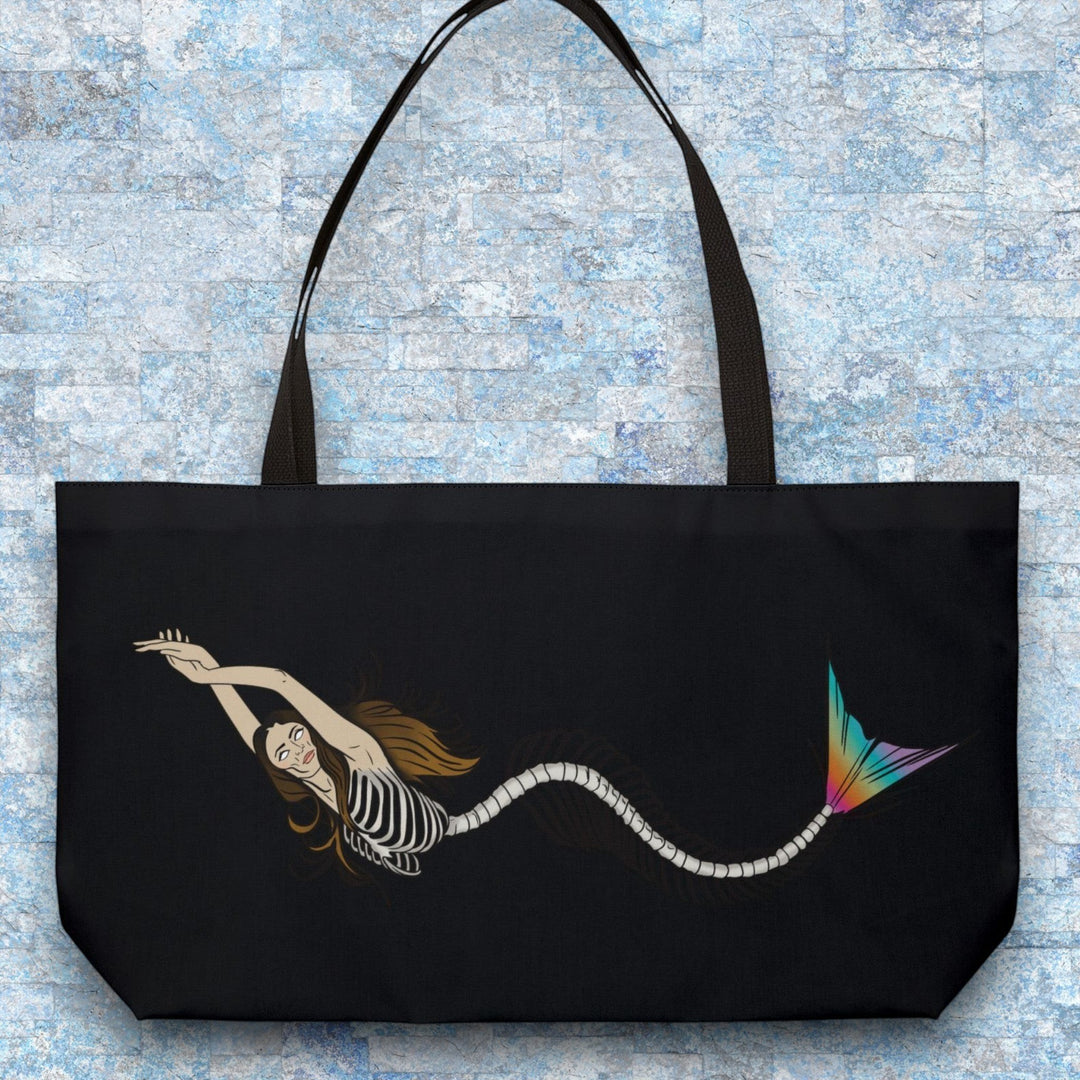 Sea Dragon Dreams weekender tote bag featuring a mermaid skeleton illustration with a vibrant rainbow tail on black.