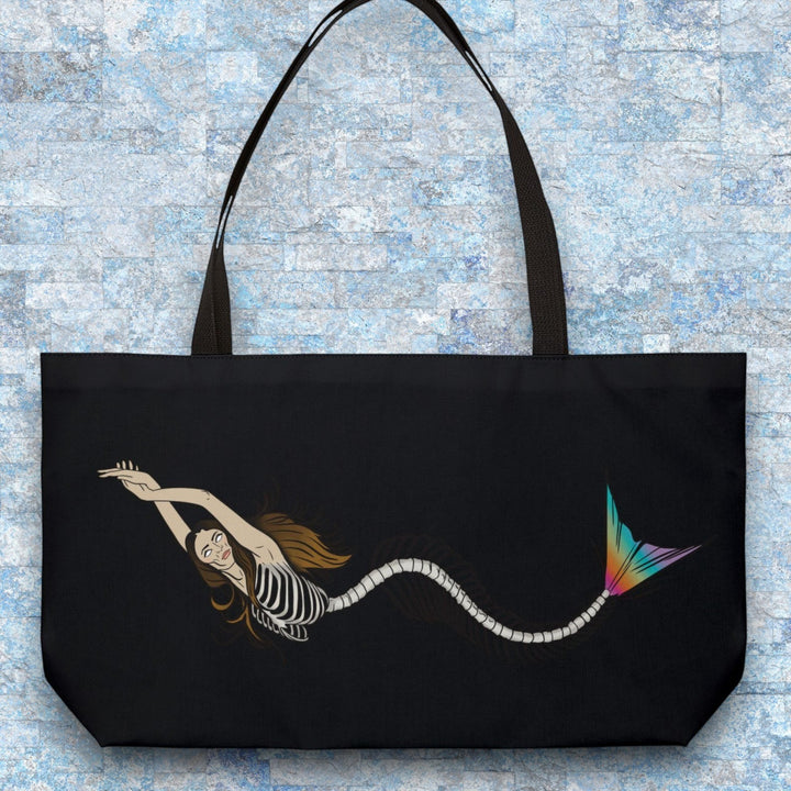 Sea Dragon Dreams weekender tote bag featuring a mermaid skeleton illustration with a vibrant rainbow tail on black.