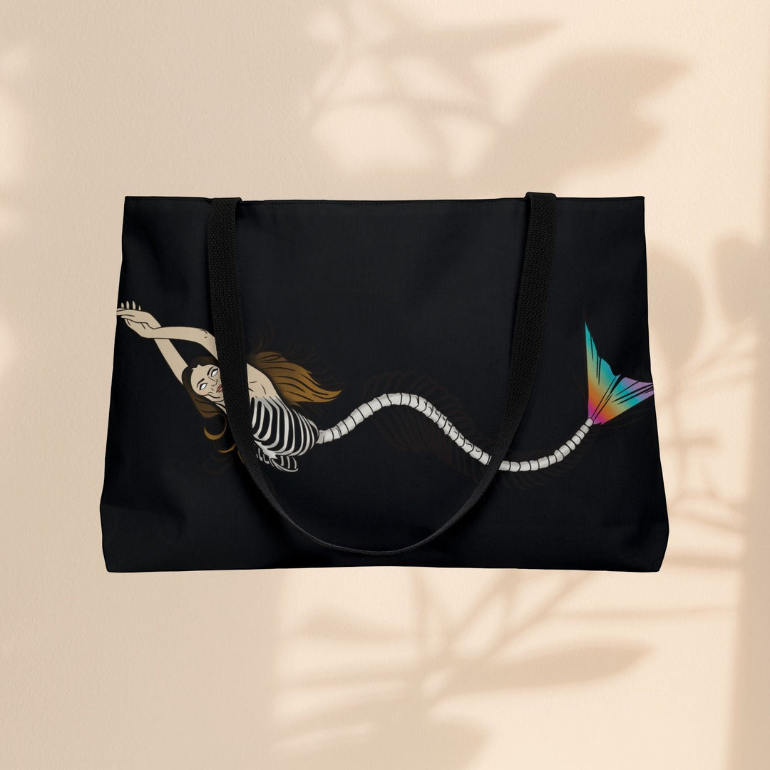 Sea Dragon Dreams weekender tote bag featuring a mermaid skeleton illustration with a vibrant rainbow tail on black