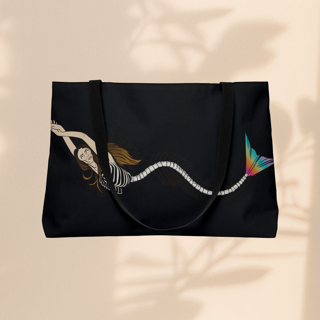 Sea Dragon Dreams weekender tote bag featuring a mermaid skeleton illustration with a vibrant rainbow tail on black