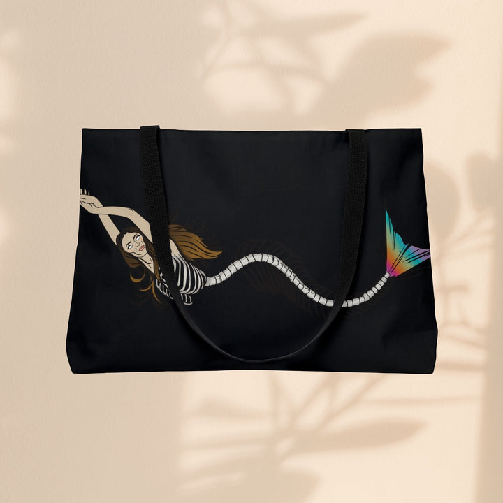 Sea Dragon Dreams weekender tote bag featuring a mermaid skeleton illustration with a vibrant rainbow tail on black