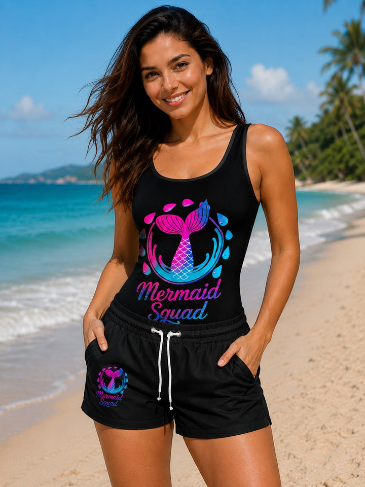 Sea Dragon Dreams vintage-style black one-piece swimsuit with Mermaid Squad graphic on a smiling woman at the beach