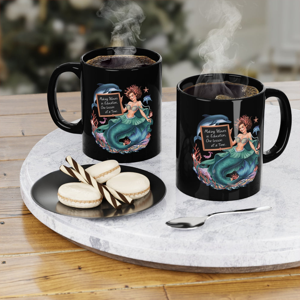 Sea Dragon Dreams black ceramic coffee mugs featuring a mermaid teacher illustration and steam on a marble table.