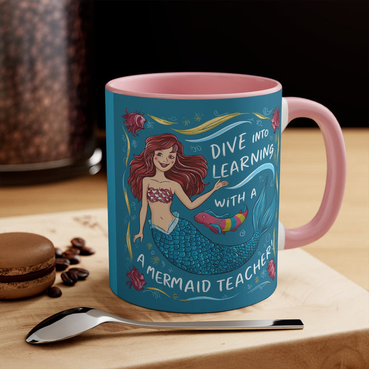 Sea Dragon Dreams ceramic accent mug with pink handle and mermaid teacher illustration on a wooden table