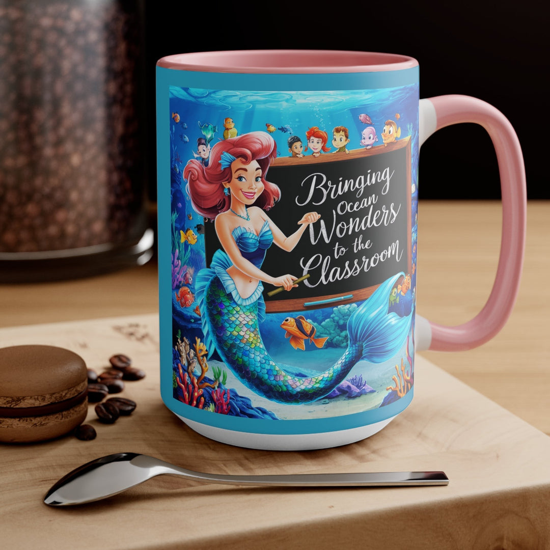 Sea Dragon Dreams ceramic mug with a mermaid teacher illustration and pink handle on a wooden table with a spoon.