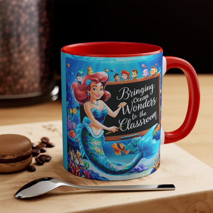 Sea Dragon Dreams ceramic accent mug with a red handle and a mermaid teacher illustration in an underwater classroom.