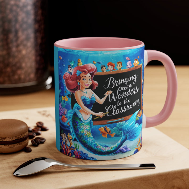 Sea Dragon Dreams ceramic mug with a mermaid teacher illustration, pink handle, and ocean-themed classroom design.