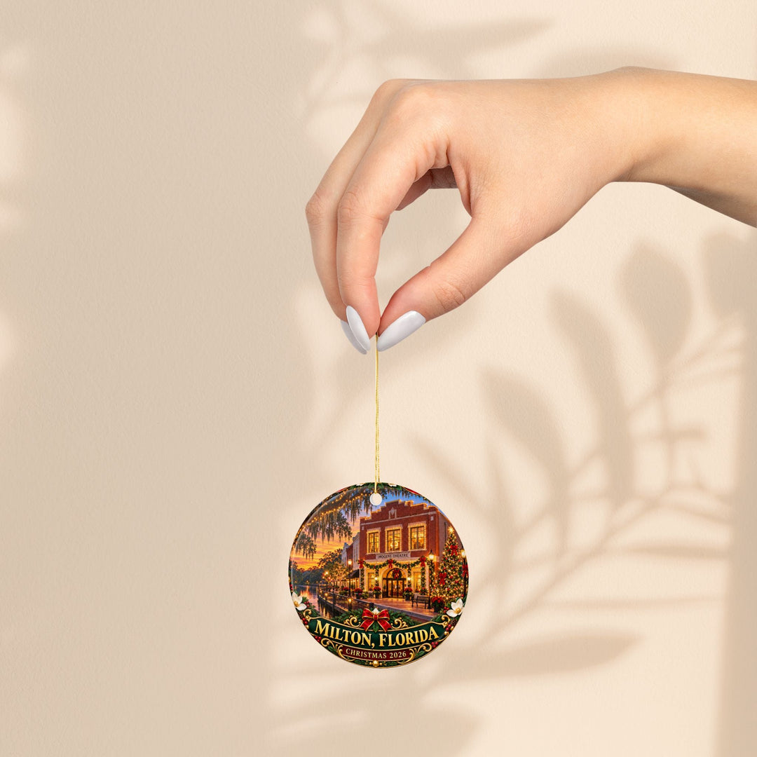 Sea Dragon Dreams round ceramic Christmas ornament featuring a Milton Florida 2026 holiday scene held by a hand.