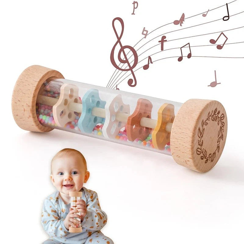 Sea Dragon Dreams Montessori rainbow rain stick rattle held by a smiling baby, featuring wooden ends and colorful beads.