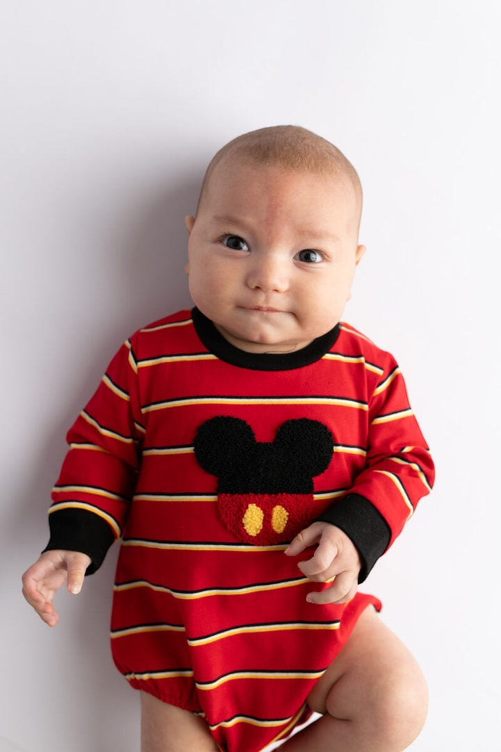 Baby wearing a Sea Dragon Dreams red striped bubble romper with a mouse-inspired applique and black trim.