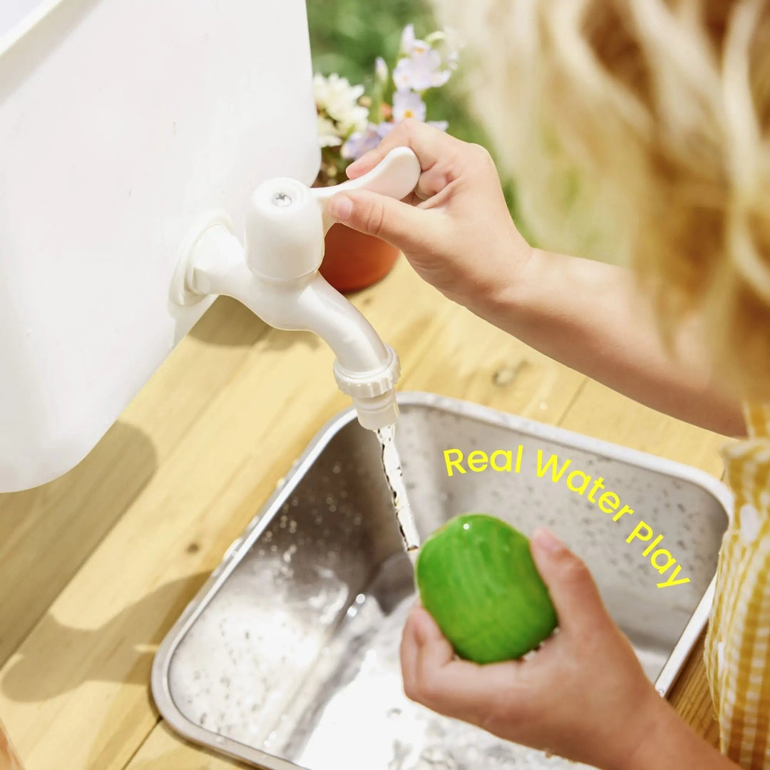 Sea Dragon Dreams Tiny Land mud kitchen featuring a child washing a toy in the stainless steel sink with a working faucet